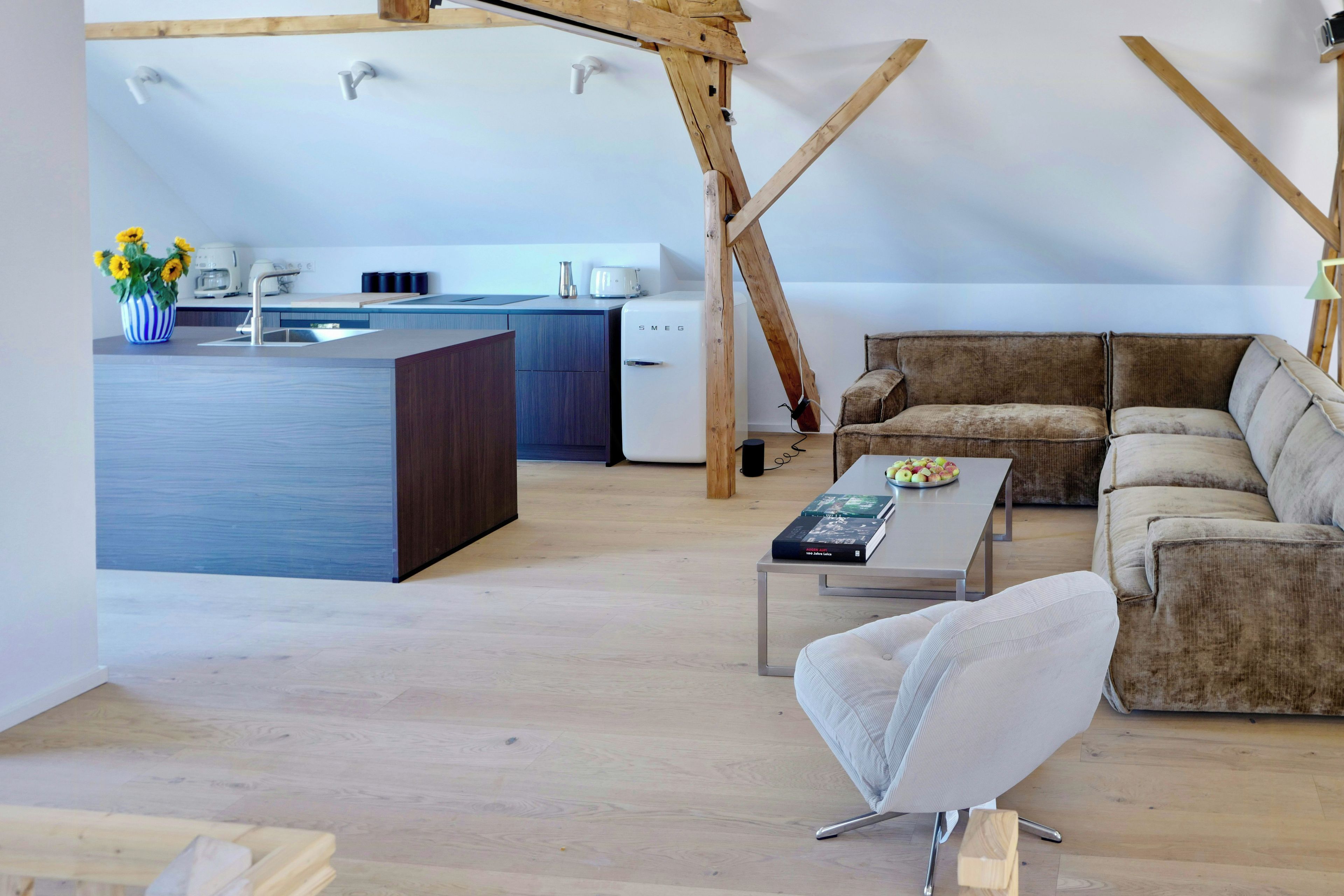 A modern loft with a kitchen, a sofa, and a coffee table.
