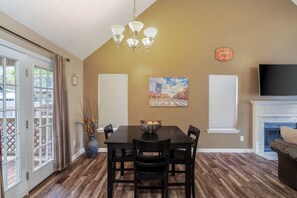 A dining area with a table and chairs, a chandelier, a painting, and a fireplace. - Quiet neighborhood home with private patio, free parking & easy airport access (Nashville)