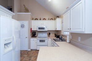 A kitchen with white cabinets, a microwave, a stove, and a sink. - Quiet neighborhood home with private patio, free parking & easy airport access (Nashville)