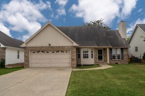 A single-story house with a garage, a brick facade, and a well-maintained lawn. - Quiet neighborhood home with private patio, free parking & easy airport access (Nashville)