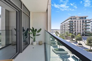 A balcony with potted plants, a view of a modern building complex, and a clear sky. - Stylish 1BR - Creek Harbour - Pool, Gym & Parking (Dubai)