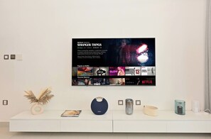 A wall with a framed poster of 'Stranger Things' and a white console table with decorative items. - Stylish 1BR - Creek Harbour - Pool, Gym & Parking (Dubai)