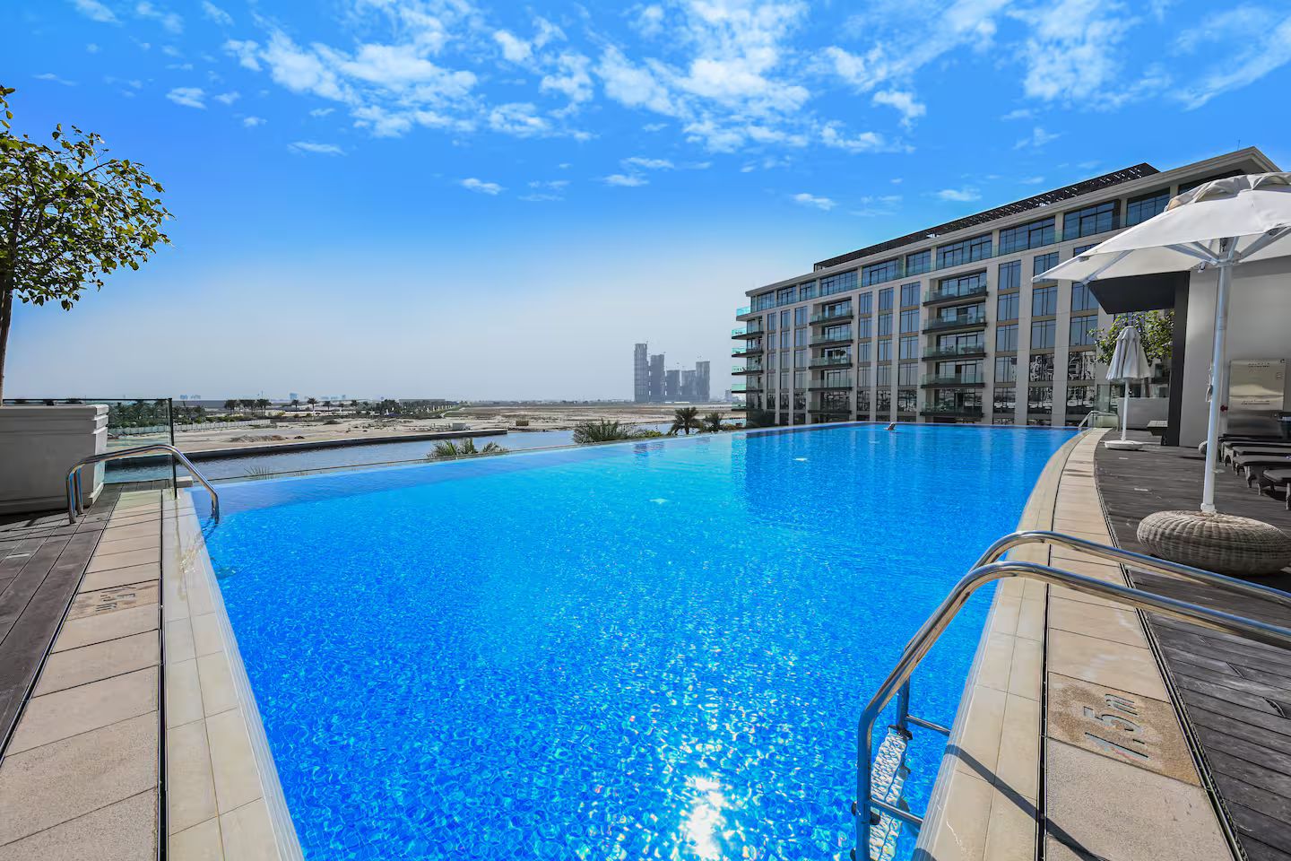 A swimming pool with a clear view of the sea and a modern building in the background.