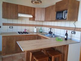 Una cocina con armarios de madera, microondas, estufa a gas y un lavamanos.