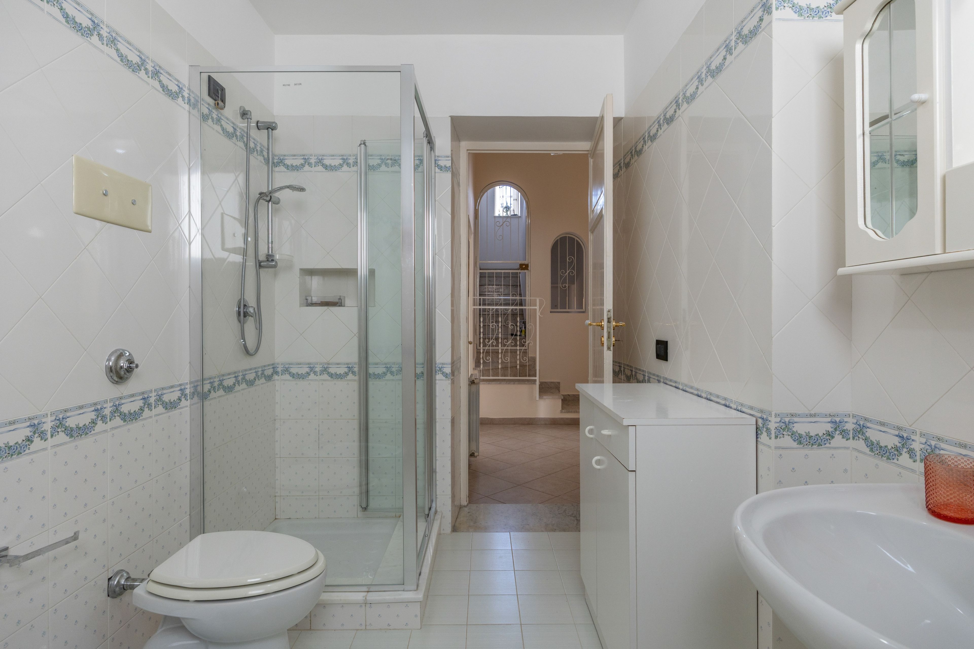 A bathroom with a glass-enclosed shower, a toilet, and a sink.