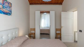 A bedroom with a bed, a chair, a wardrobe, and a door.