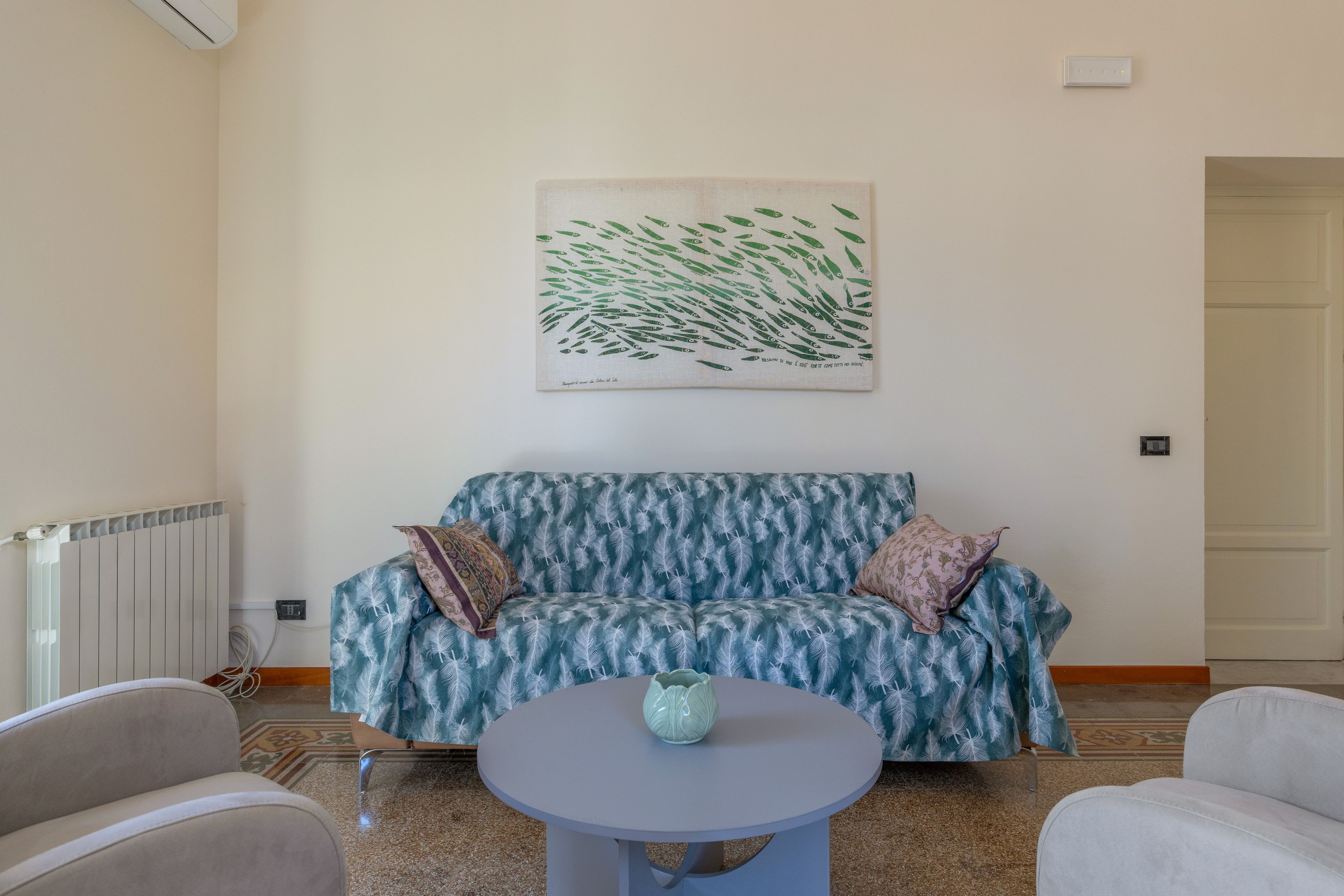 Un salon avec un canapé, une table basse et un tableau accroché au mur.