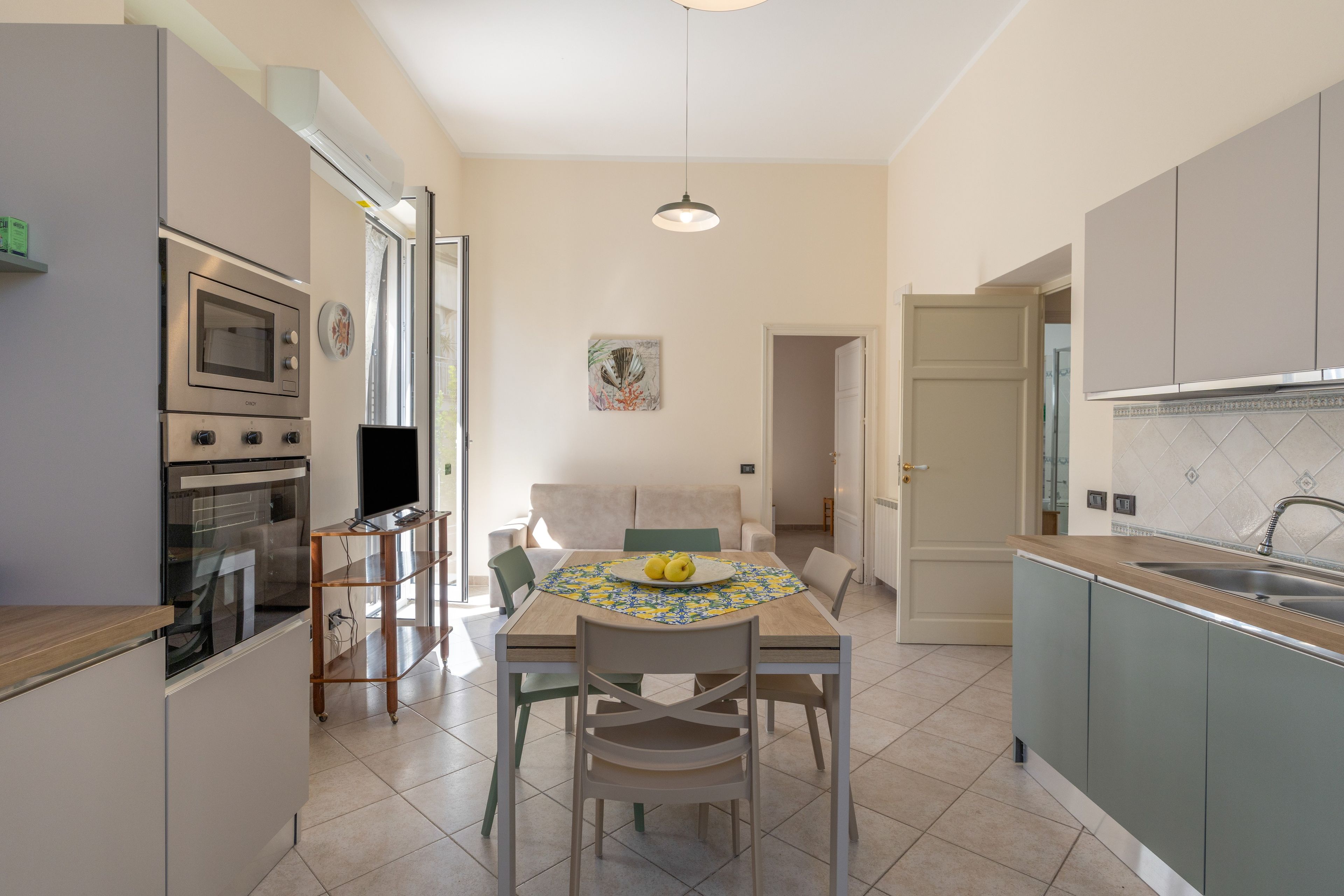 Une cuisine moderne dotée d’appareils électroménagers intégrés, une table à manger avec des chaises et une vue sur le salon attenant.