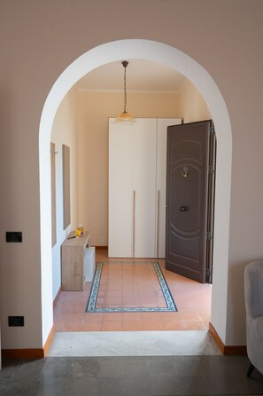 A hallway with a white door, a coat rack, and a hanging light fixture.