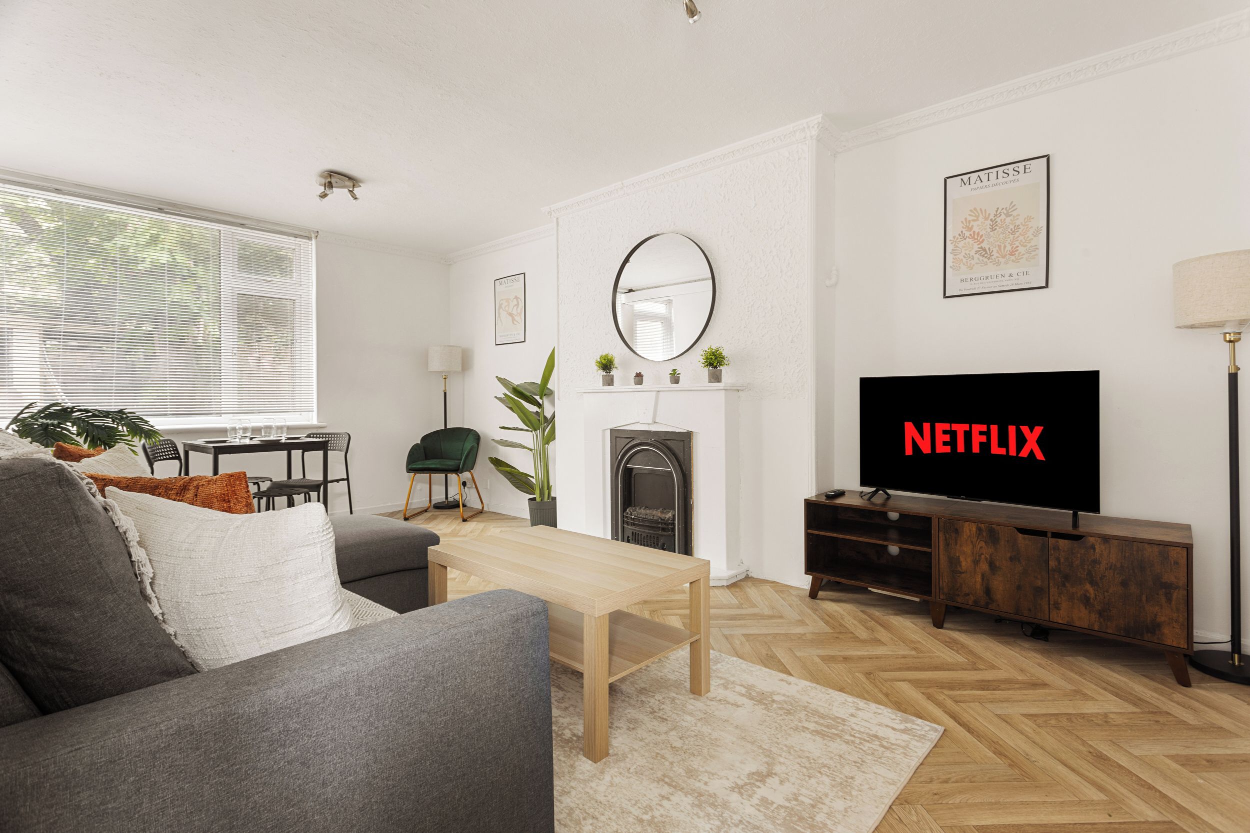A modern living room with a sofa, coffee table, fireplace, and a television displaying 'NETFLIX'.