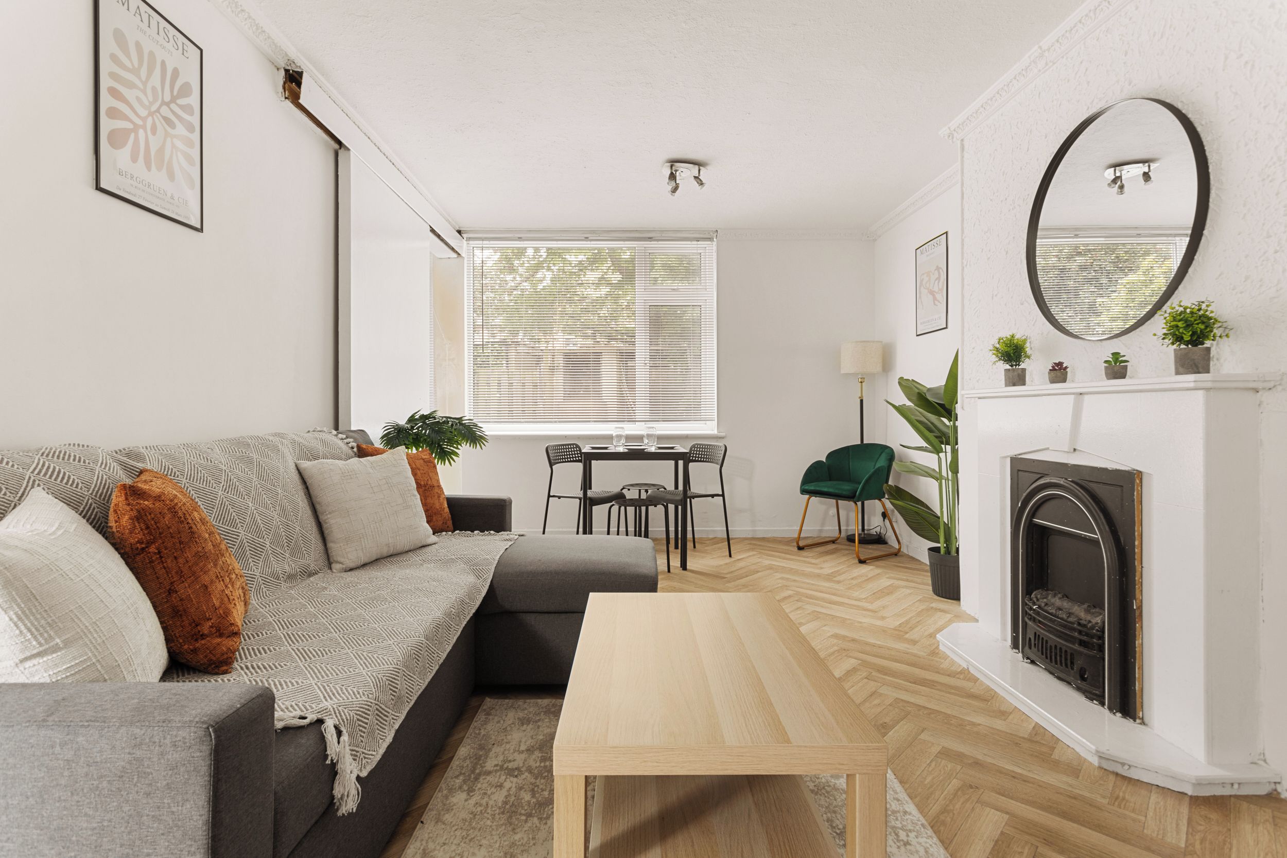 A modern living room with a sofa, coffee table, fireplace, and a dining area with a table and chairs.