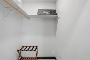 A small, enclosed room with a wooden bench, a white shelf with a Graco bag, and a white wall. - Spectacular Retreat with Private Pickleball Court (Tucson)