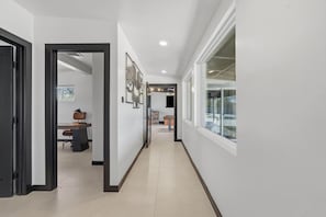 A hallway with a door leading to a room, a window, and a door at the end. - Spectacular Retreat with Private Pickleball Court (Tucson)