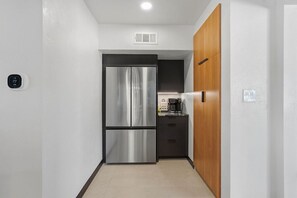 A compact kitchen with a stainless steel refrigerator, a wooden cabinet, and a coffee maker on the counter. - Spectacular Retreat with Private Pickleball Court (Tucson)