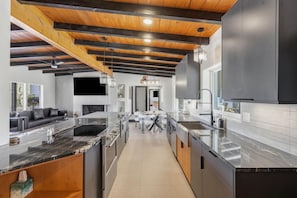 A modern kitchen with a marble countertop, wooden ceiling beams, and a central island. - Spectacular Retreat with Private Pickleball Court (Tucson)