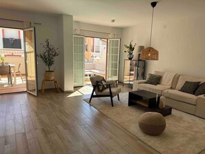 A modern living room with a sofa, armchair, coffee table, and a large window. - Apartment 'Burriana Bliss Nerja' with Mountain View, Wi-Fi and Air Conditioning (Nerja)
