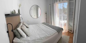 A bedroom with a bed, a mirror, a wardrobe, and a view of the outdoors through a sliding door. - Apartment 'Burriana Bliss Nerja' with Mountain View, Wi-Fi and Air Conditioning (Nerja)