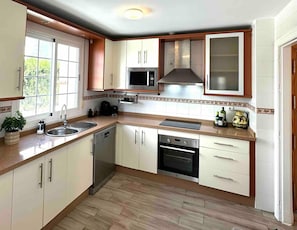 A kitchen with white cabinets, a stainless steel microwave, a built-in oven, and a sink. - Apartment 'Burriana Bliss Nerja' with Mountain View, Wi-Fi and Air Conditioning (Nerja)