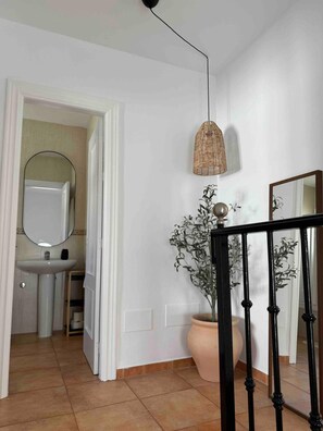 A hallway with a white wall, a black railing, a hanging light fixture, and a potted plant. - Apartment 'Burriana Bliss Nerja' with Mountain View, Wi-Fi and Air Conditioning (Nerja)