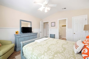A bedroom with a bed, dresser, television, and a ceiling fan. - Moore Fun by Brunswick Vacation Rentals - Canal Front Oasis w/ Pool & Tiki Bar (Ocean Isle Beach)