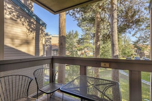 A covered outdoor area with two metal chairs and a table, overlooking a residential neighborhood with houses and trees. - Lake days, mountain adventures & resort amenities right outside your door (South Lake Tahoe)
