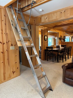 A wooden interior with a metal ladder, a dining area, and a brown leather couch.