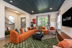 Ein Wohnzimmer mit einer Eckcouch, einem Couchtisch und einem Fernseher.