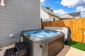 Ein Whirlpool in einem Garten mit Holzzaun und einem Haus im Hintergrund.