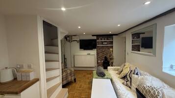 A living room with a sofa, a coffee table, a fireplace, and a television mounted on the wall.
