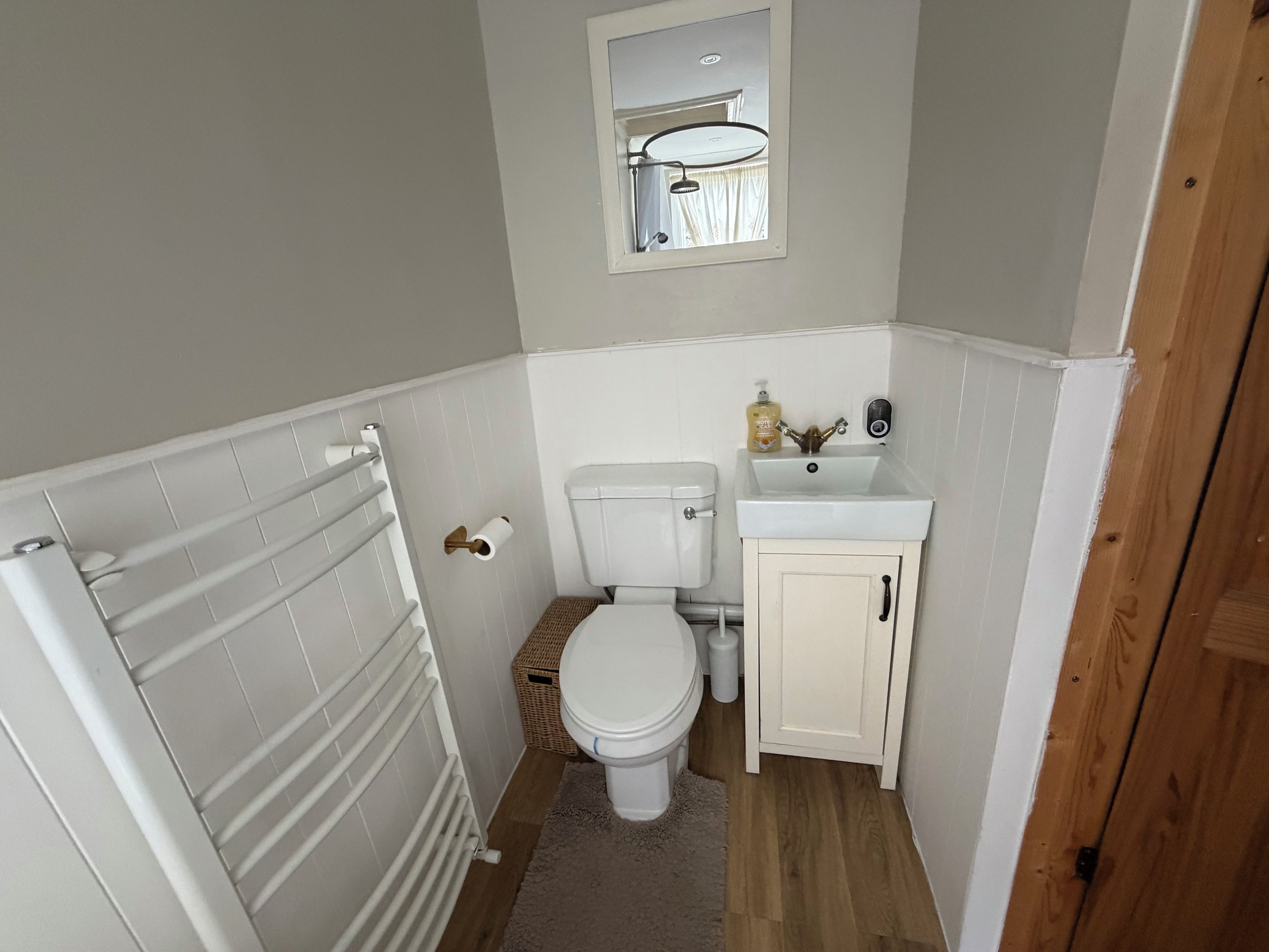 A compact bathroom with a toilet, a sink, and a mirror.
