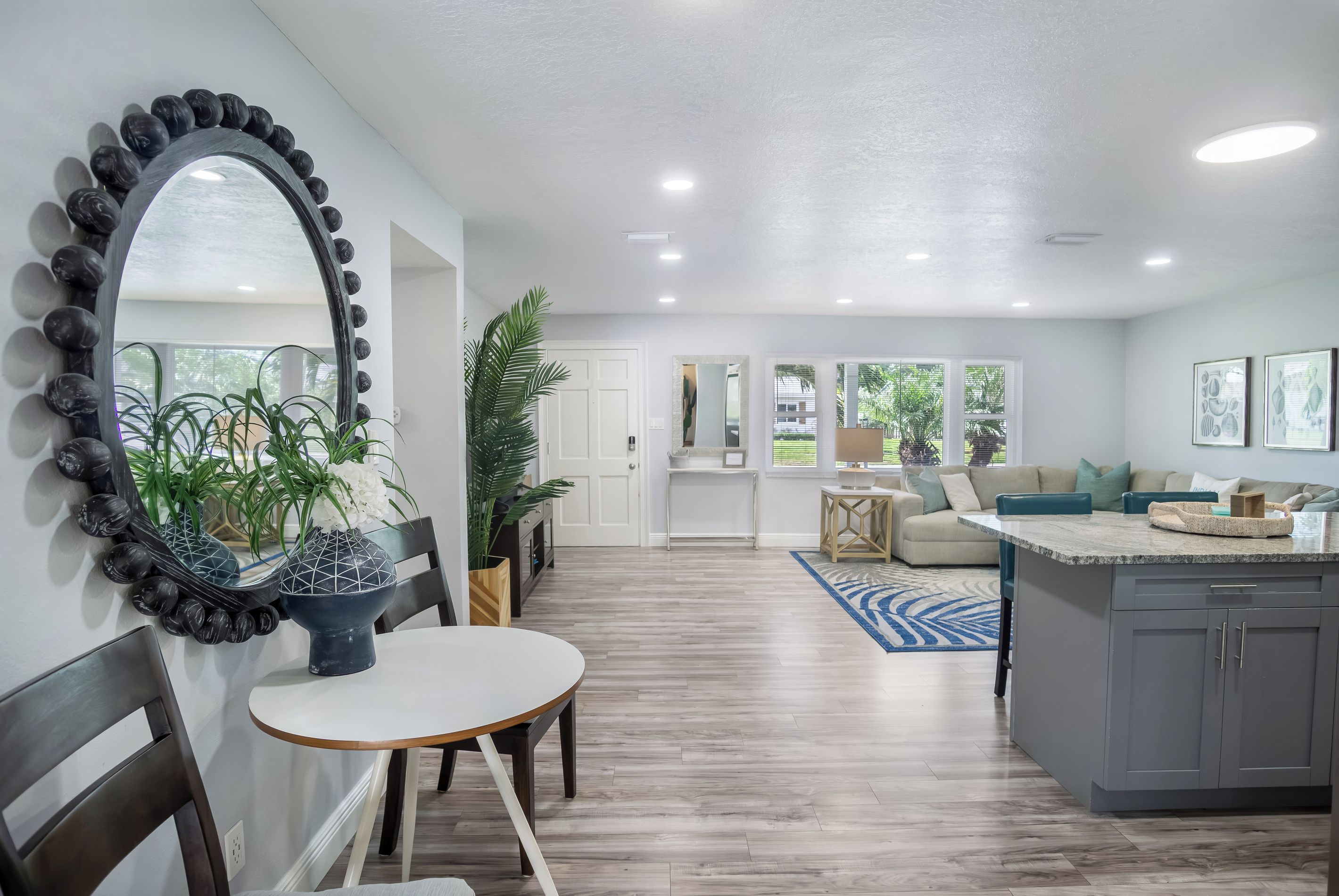 Una cocina moderna con una isla central, una zona de comedor con mesa redonda y un pasillo que conduce a una sala de estar.