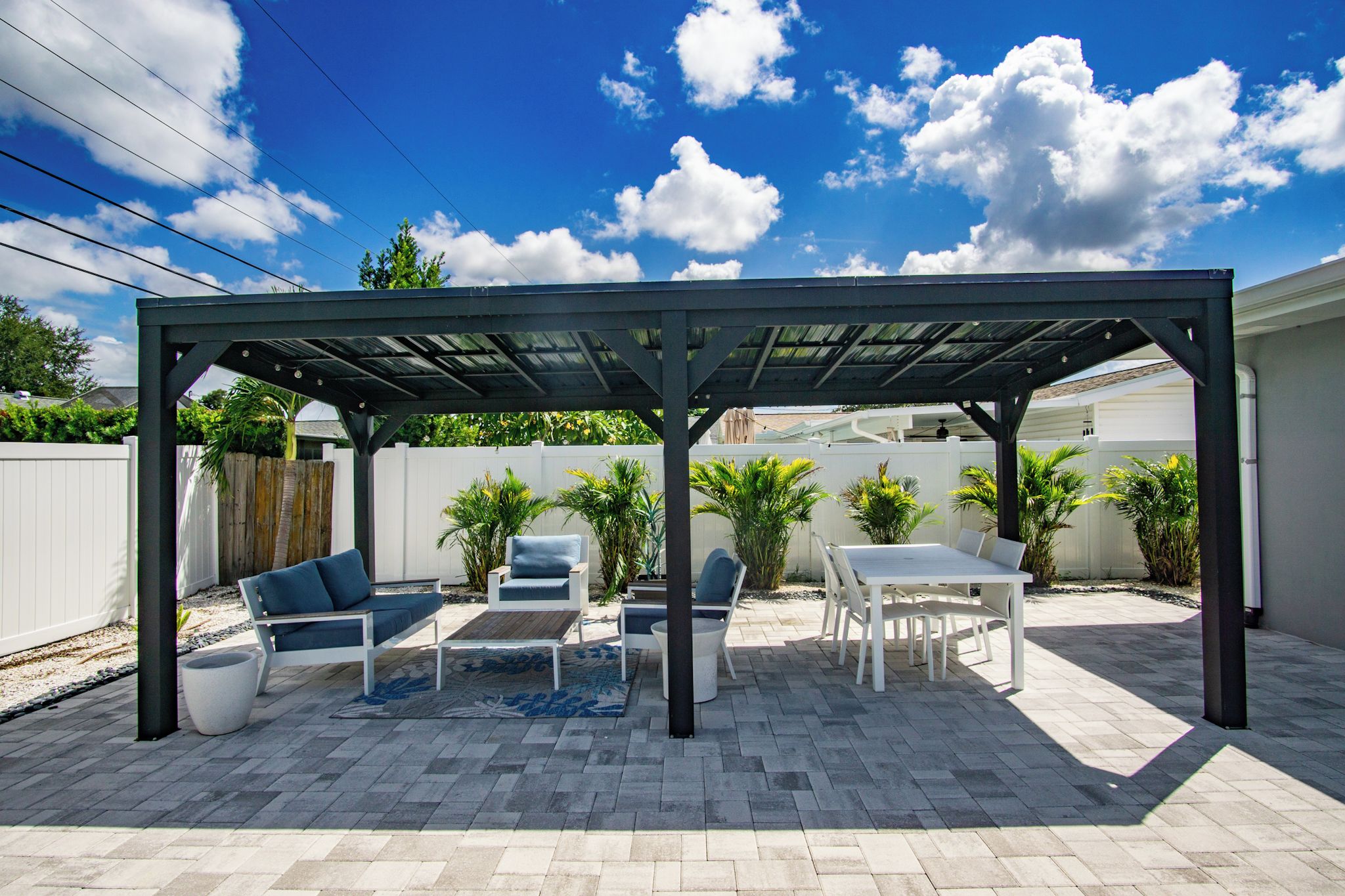 Ein überdachter Patio-Bereich mit Gartenmöbeln, einem Tisch und einer Pergola.