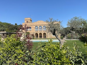 A large building with multiple arches and a tower, surrounded by well-maintained greenery and a pool. - Apartment 'Mas Moré Petit' with Shared Pool, Wi-Fi and Air Conditioning (Vulpellac)