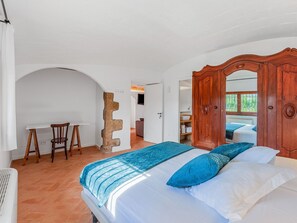 Une chambre à coucher avec un lit, une armoire en bois et un mur en pierre.