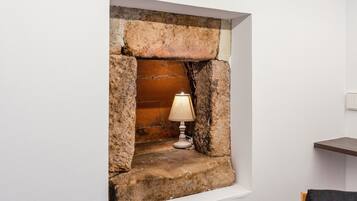 Una chimenea con una lámpara, integrada en una pared blanca de piedra.
