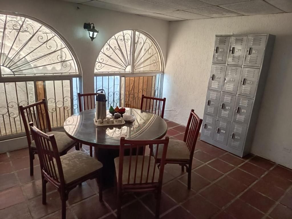 Uma sala de jantar com uma mesa redonda, seis cadeiras e um objeto decorativo no centro.