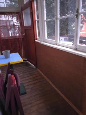 A room with a wooden floor, a window with white frames, and a view of trees and buildings outside. - Vollmöbliertes 4-Zimmer-Haus in Pforzheim (Pforzheim)