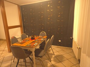 A dining area with a wooden table, four chairs, and a black textured wall. - Vollmöbliertes 4-Zimmer-Haus in Pforzheim (Pforzheim)