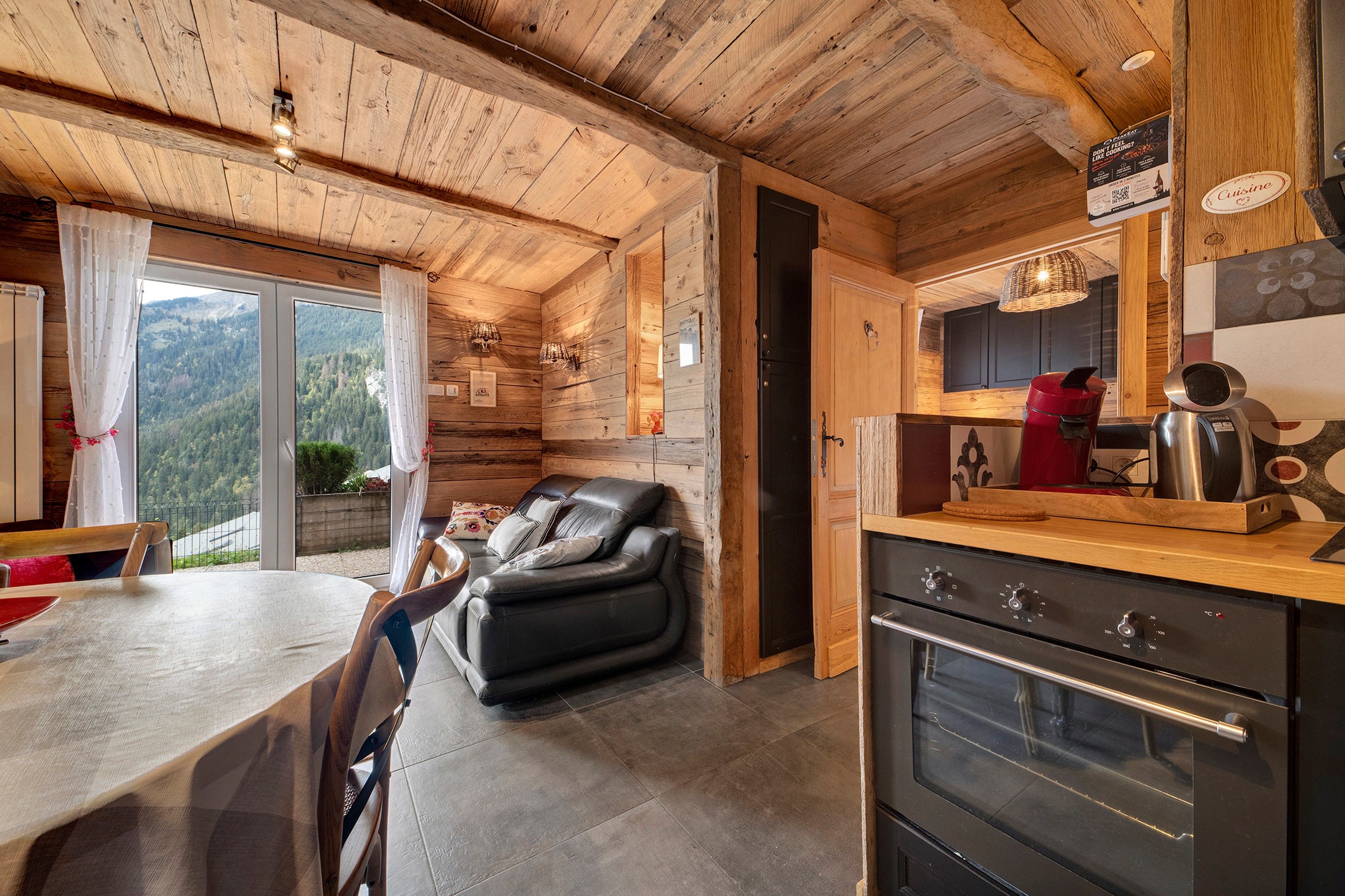 L’intérieur chaleureux d’un chalet comprend un coin repas, un canapé et une cuisine équipée d’une cuisinière.
