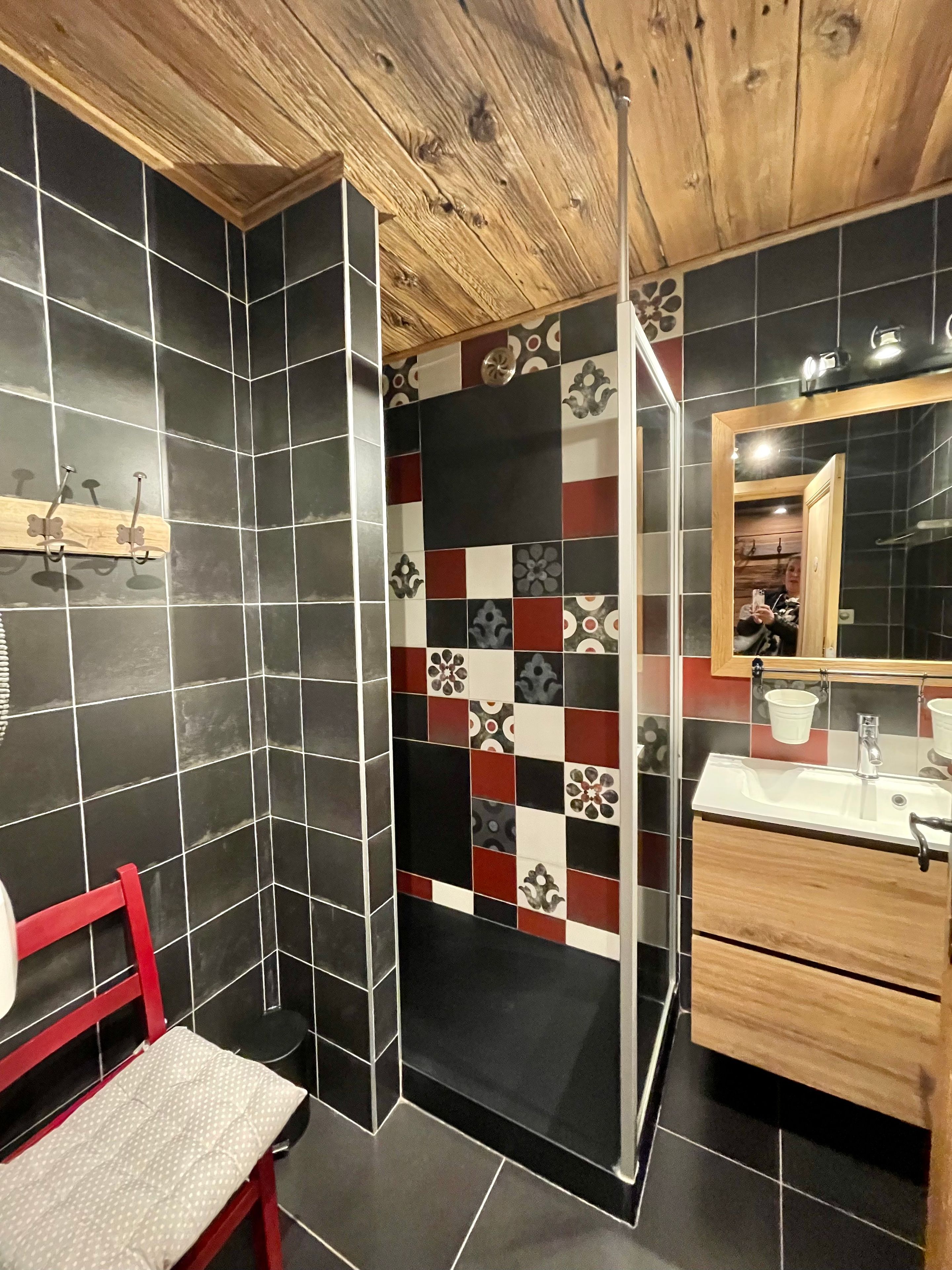 Une salle de bain avec un plafond en bois, un miroir, un lavabo et un banc.