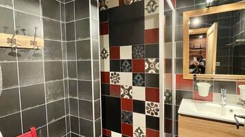 Une salle de bain avec un plafond en bois, un miroir, un lavabo et un banc.