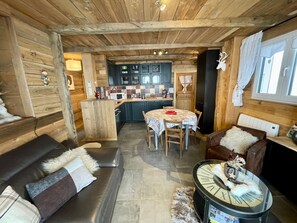 Un intérieur de chalet chaleureux comprenant un coin repas, une cuisine et un espace salon.