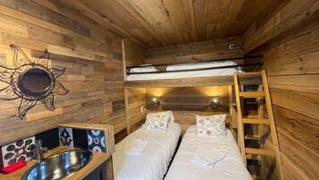 Une petite pièce avec un lit superposé, un petit lavabo et un miroir au mur.