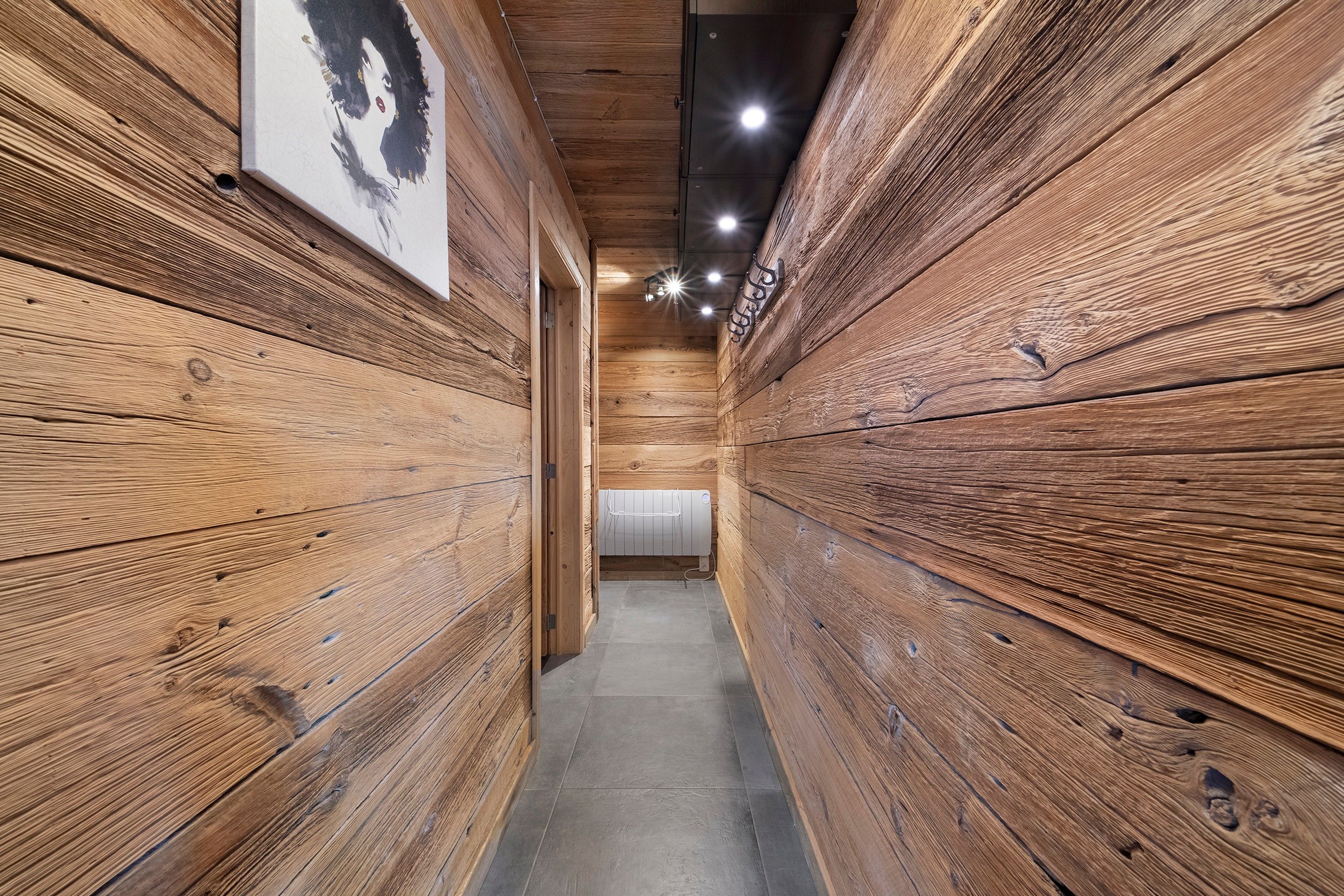 A narrow hallway with wooden paneling on the walls and a radiator on the floor.