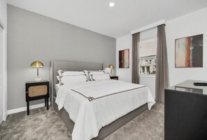 A modern hotel room with a large bed, bedside lamps, a desk, and artwork on the walls. - 9BR house sleeps 24 with hot tub and pool (Kissimmee)