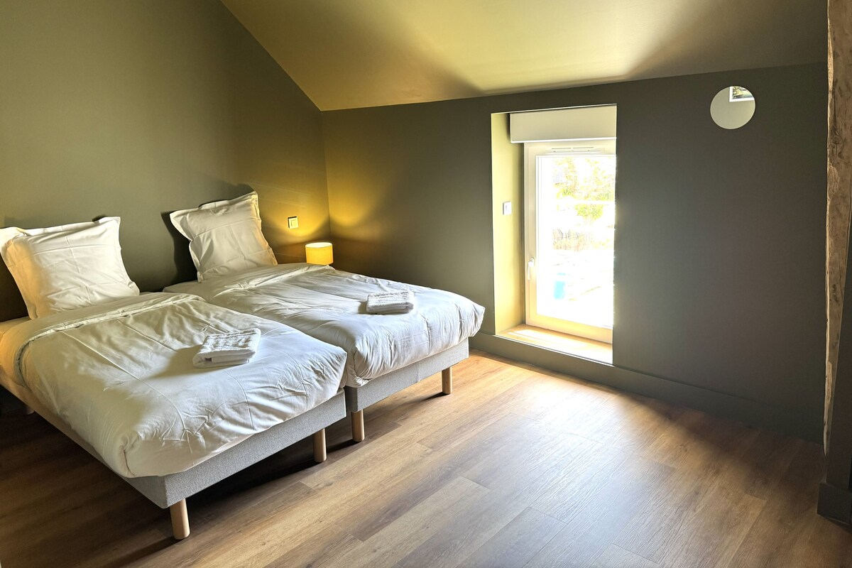 Un dormitorio con dos camas, una ventana y una lámpara de noche.
