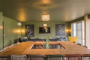 A conference room with a large wooden table, multiple chairs, a chandelier, and educational posters on the walls.