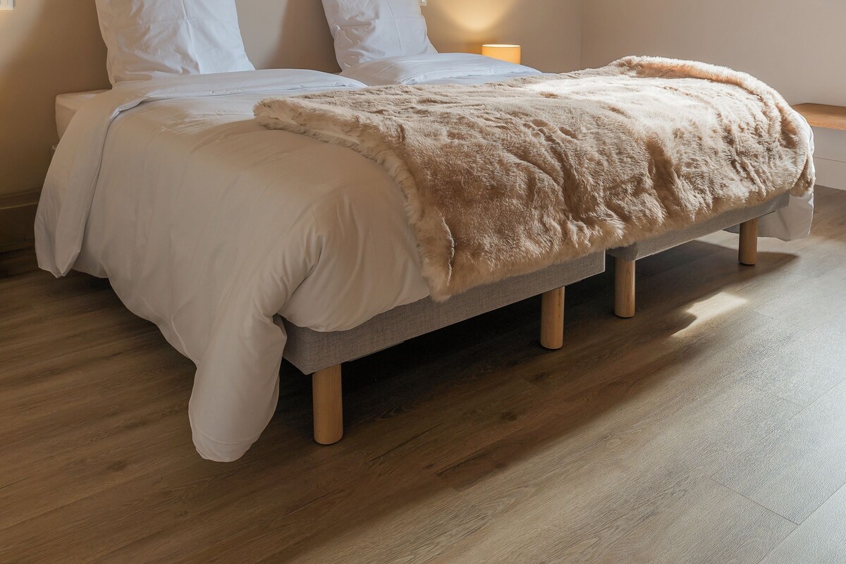 Un dormitorio con cama, vigas de madera, un cuadro enmarco y una mesita de noche.