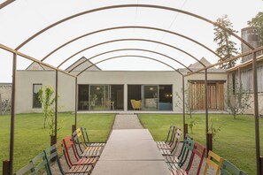 A covered outdoor seating area with a pathway leading to a modern building with large glass doors.