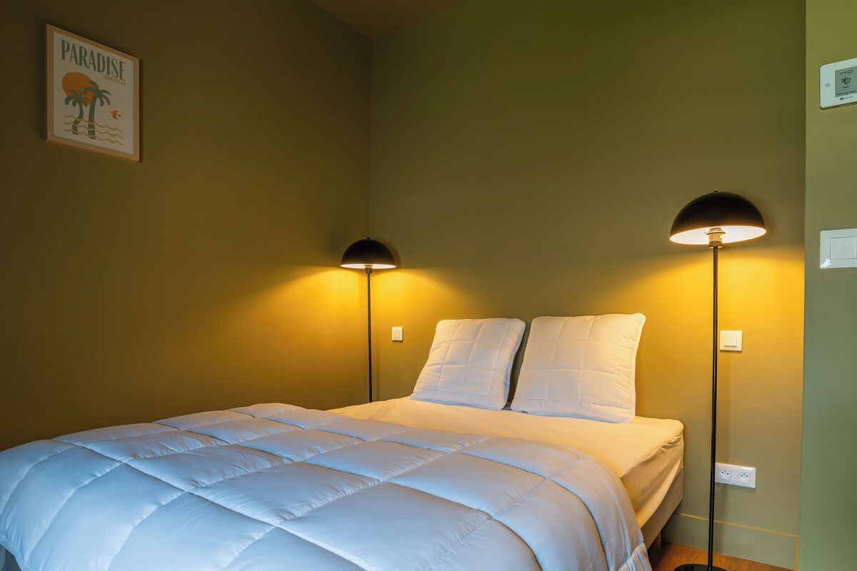 Un dormitorio con cama, dos lámparas de noche y un interruptor de luz en la pared.